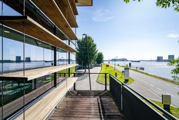 Modern kantoorgebouw aan de Rivium Promenade met uitzicht op de rivier en omliggende hoogbouw.